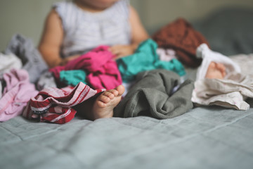 Funny Caucasian baby playing with bunch of clothes