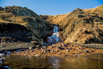 Orange waterfall from below, framed by rock