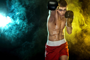 Sportsman, man boxer fighting in gloves. on black background with color smoke. Copy Space.