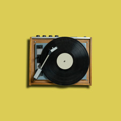 vintage turntable vinyl record player on yellow background. retro sound technology to play music