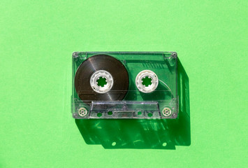 transparent audio cassette tape on green background. retro music magnetic technology