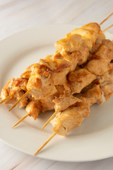 Chicken meat on bamboo skewers kebab in white plate, marble bright background. Diet low fat food.