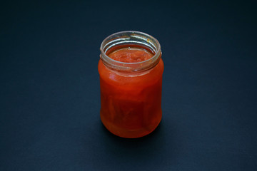 Glass jar of jam on a dark background