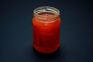 Glass jar of jam on a dark background