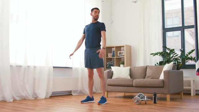 fitness, sport and healthy lifestyle concept - man exercising and doing squats at home