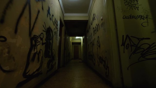 Old Apartment,Ghetto Building,long Dark Hallway.Tracking inside a dark long hallway of a ghetto apartment complex.Graffiti vandalism and abandonment in a poverty stricken neighbourhood.