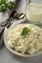 Cottage cheese isoalted on light, marble background. Dairy products, calcium and protein. Healthy breakfast. Vertical image.