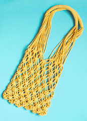 Handmade yellow macrame bag on the light blue background, ECO friendly. Modern summer beach concept