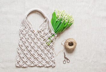 Handmade macrame bag on the linen background, ECO friendly. Embroidery. Modern summer concept. Lily...
