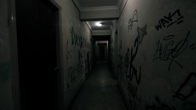 Old Apartment,Ghetto Building,long Dark Hallway.Tracking inside a dark long hallway of a ghetto apartment complex.Graffiti vandalism and abandonment in a poverty stricken neighbourhood.