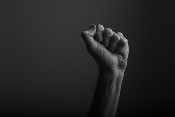 Raised clenched fist against a dark background, power, protest concept - obrazy, fototapety, plakaty