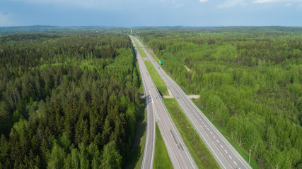 Fototapeta premium Straight highway through deep forest aerial view. Bright summer image. FInland