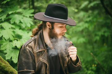 Film photo. Portrait of bearded man in hat smoking tobacco pipe.