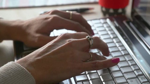 esplazamiento de izquierda a derecha de la camara donde se observa las manos de una mujer tecleando una computadora en plano cerrado