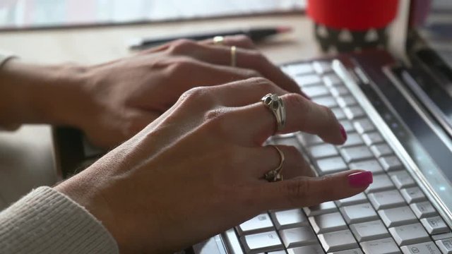desplazamiento de derecha a izquierda de la camara  donde se observa las manos de una mujer tecleando una computadora en plano cerrado
