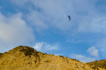Fototapeta na wymiar Man doing sport (Para-glider). Man paragliding in the clouded sky. Paragliding is an extreme sport and recreation. Torrey Pines Gliderport. San Diego. California, USA.