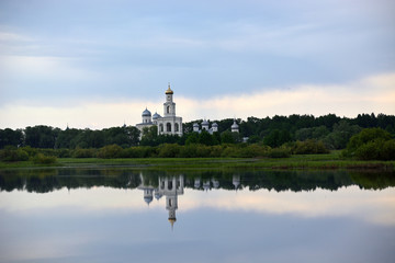 Fototapeta na wymiar Yurievsky monastery with a beautiful reflection in the lake. Summer view with a cloudy sky.Lake Myachino Novgorod region