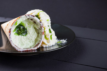 Ice cream cone on black background, summer concept. Dessert with jam on black plate. Waffle cone with ice cream in minimalism style. Copy space