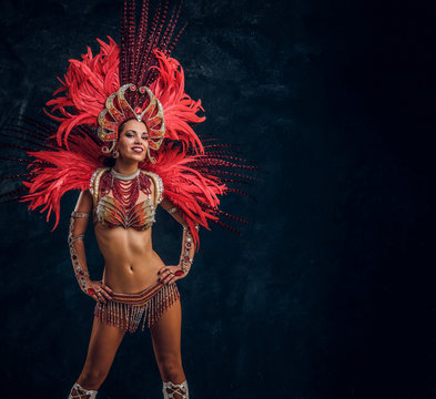 Happy beautiful brasil dancer in red feather costume is dancing on small scene.