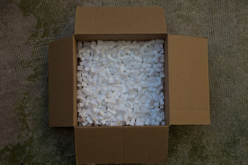cardboard box with packing foam pellets white polystyrene foam, styrofoam popcorn or packing noodles used to cushion the contents of packages while shipping commonly made of expanded polystyrene foam