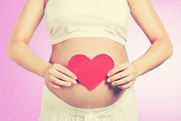 Close up of a cute pregnant belly and red heart