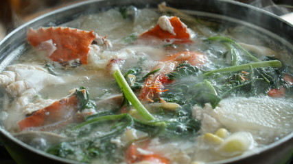 Boiling seafood soup with shrimps, crabs, clams and vegetables cooked in Jagalchi fish market in South Korea in Busan.