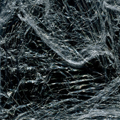 Transparent plastic wrap on the black background. Plastic bag texture. Reusable trash and waste.