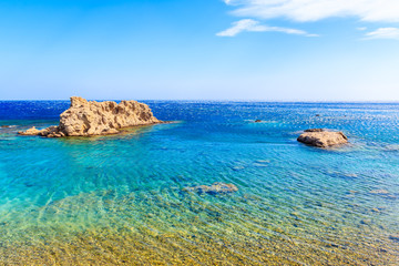 Fototapeta na wymiar Rocks in crystal clear azure sea near beach on Karpathos island near Ammopi village, Greece