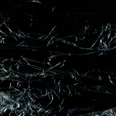 Transparent plastic wrap on the black background. Plastic bag texture. Reusable trash and waste.