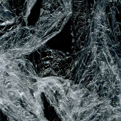Transparent plastic wrap on the black background. Plastic bag texture. Reusable trash and waste.