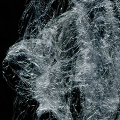 Transparent plastic wrap on the black background. Plastic bag texture. Reusable trash and waste.