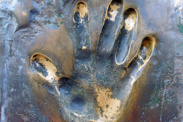 Prints of human hand. The imprint of the left palm on the surface of bronze close-up.