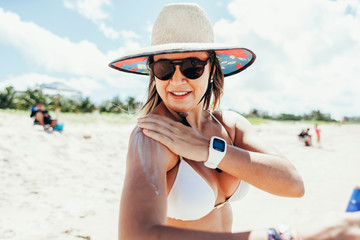 Sunscreen, sunblock. Woman putting solar cream on shoulder smiling beautiful summer day. Skincare. Girl applying sun cream