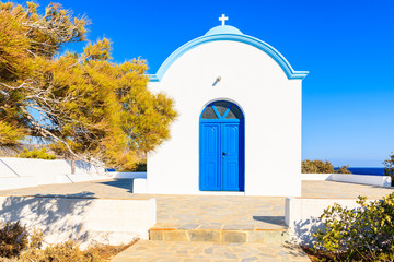 Naklejka premium Facade of white typical Greek church with blue door on coast of Karpathos island, Ammopi village, Karpathos island, Greece