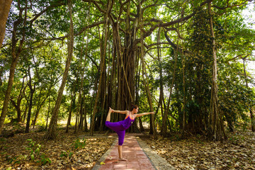 Woman makes yoga  on a background jungle.