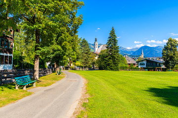 Path in Kitzbuhel town park with church towers in distance in summertime, Tirol, Austria