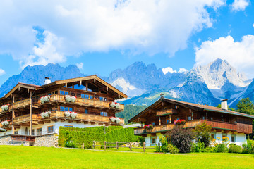 Fototapeta na wymiar Traditional alpine houses in village of Going am Wilden Kaiser on beautiful sunny summer day with Alps mountains in background, Tirol, Austria