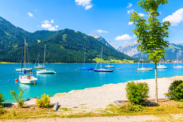 Sailing boats and view of beach near Pertisau town at beautiful Achensee lake on sunny summer day, Tirol, Austria