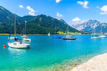 Fototapeta na wymiar Sailing boats and view of beach near Pertisau town at beautiful Achensee lake on sunny summer day, Tirol, Austria