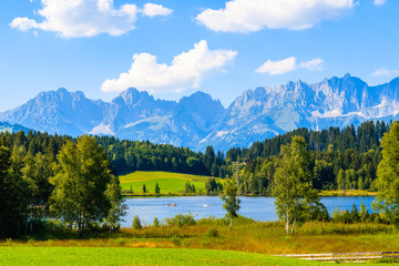 Green meadow against Alps mountains near Schwarzsee lake on sunny beautiful summer day near Kitzbuhel, Tyrol, Austria