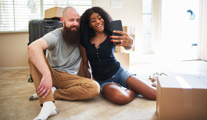 interracial couple taking selfie together while moving into new home