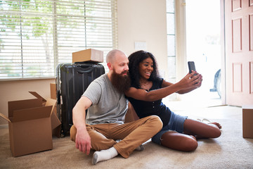 Fototapeta na wymiar interracial couple taking selfie together while moving into new home