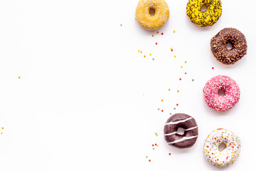 Donuts of different flavors for breakfast on white background top view