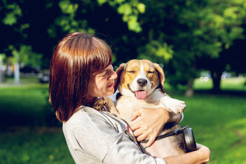 Girl holding a dog in her arms on the nature background at summer time. Lifestyle photo.