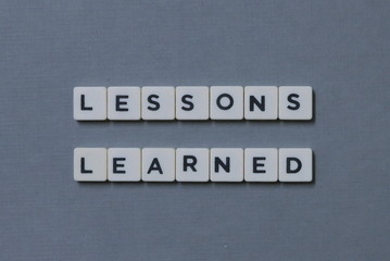 ' Lessons Learned ' word made of square letter word on grey background.
