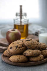 Pile of Delicious Chocolate Chip Cookies on a plate with glass of milk on wooden table