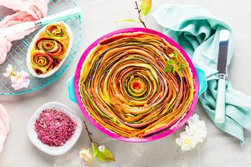 Spiral vegetable tart on colorful decorated table.