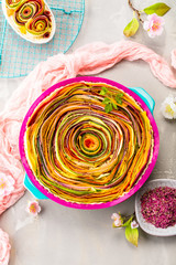 Spiral vegetable tart on colorful decorated table.