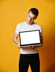 A handsome young man holding and showing the screen of a laptop