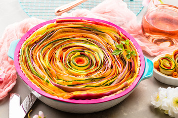 Spiral vegetable tart on colorful decorated table.